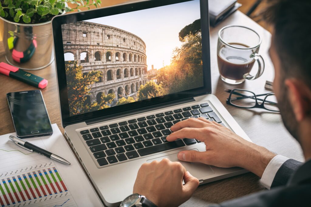 Professionista al lavoro su un laptop con immagine del Colosseo, simbolo di Roma, rappresentando la Consulenza Fiscale Personalizzata di uno studio commercialista di Roma.